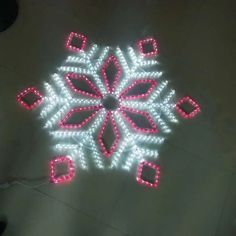 a lighted snowflake on the ground with red and white lights in the middle