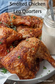 grilled chicken leg quarters on a plate next to a jar of ranch dressing with the words, smoked chicken leg quarters