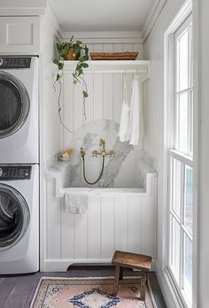 a washer and dryer in a white laundry room with wood flooring on the side