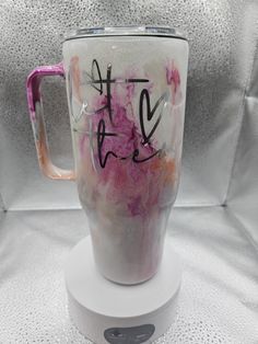 a pink and white coffee cup with the word love painted on it's side