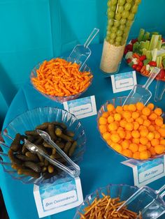 a table topped with bowls filled with different types of food next to plastic containers full of carrots, pickles and celery