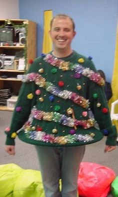 a man standing in front of a christmas tree sweater