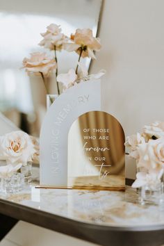 a table topped with flowers and vases filled with pink roses next to a mirror