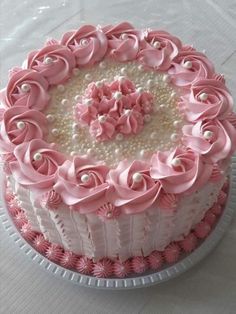 a pink and white decorated cake on a table