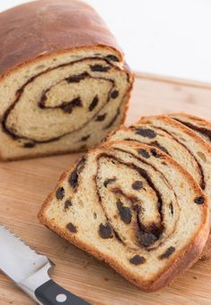 a sliced loaf of chocolate swirl bread on a cutting board with a knife next to it