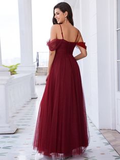 a woman in a red dress standing on a tile floor with her back to the camera