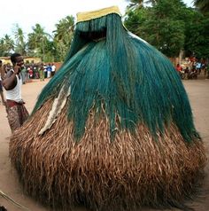 a man standing in front of a green and brown structure with grass on it's roof