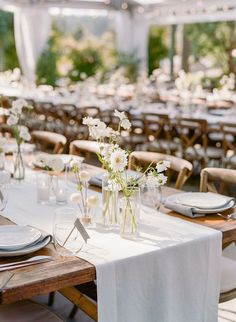 the tables are set with white flowers in vases and place settings for dinner guests