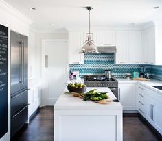 a kitchen with white cabinets and blue backsplashes on the counter top, along with a large bowl of vegetables