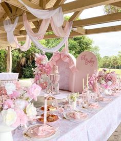 a table set up for a baby shower with pink and white flowers on the table