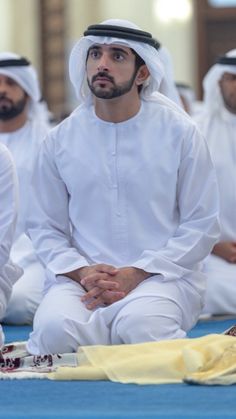 two men sitting on the floor in front of each other with their hands clasped together