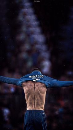 the back of a man with his arms stretched out in front of him, wearing blue shorts