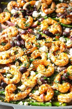 a pan filled with shrimp, olives, and feta cheese on top of it