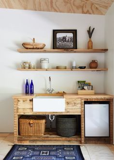 a bathroom with shelves and a sink in the corner, next to a rug on the floor