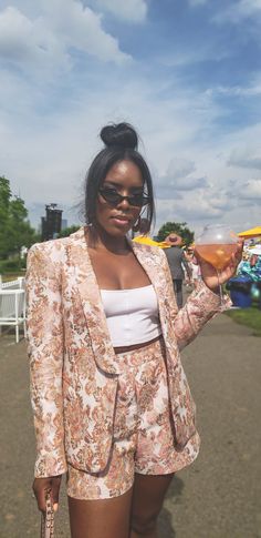 a woman holding a drink in her right hand and wearing sunglasses on the other side