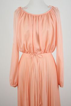 "1970s maxi dress. Peach colored light weight sheer polyester fabric on the outside and lined with an opaque nylon fabric. Long sleeves are unlined and are open from the shoulder to about the elbow with elastic at the wrists. Blousy top, elastic waist, and accordion pleated skirt. There is not a lot of stretch to the waist. Skinny fabric cord belt. Fastens down the back with a metal zipper. Only labels are a size 11/12, ILGWU, and dry clean only. Freshly laundered. (I have to laugh when polyeste 1970s Dresses, Hawaiian Dress, Peasant Dress, Skirt Suit, Yellow Dress, Pleated Skirt, Skirt Set, Polyester Fabric, Vintage Dresses