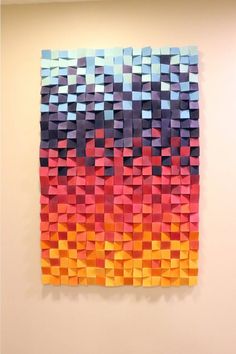 an art piece made out of colored paper on a wall with white walls and flooring