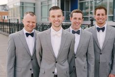 three men in suits and bow ties are smiling for the camera while standing next to each other