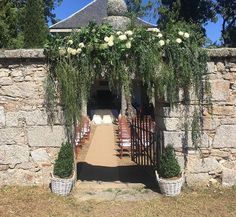 an outdoor wedding venue set up with white flowers and greenery on the wall, surrounded by stone walls