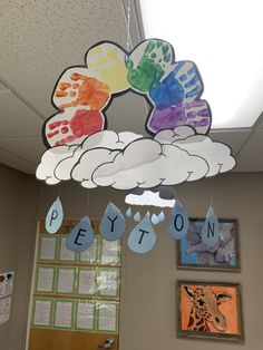 a classroom decorated with paper clouds and handprints on the ceiling, hanging from hooks