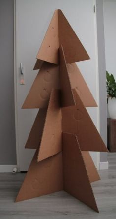 a cardboard christmas tree sitting on top of a wooden floor