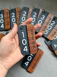 a hand holding a wooden keychain with numbers and date tags on the front