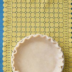 a pie crust sitting on top of a yellow placemat next to a blue table