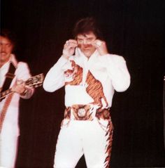 two men in elvis style clothing are standing on stage