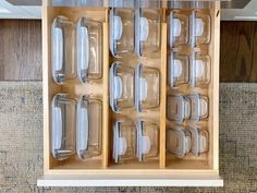 an open wooden cabinet with clear glassware in the bottom drawer and lid on top