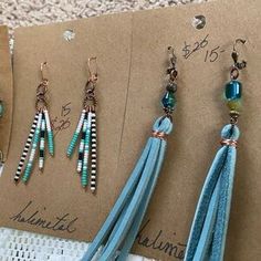 three pairs of earrings with tassels and beads on top of a piece of paper