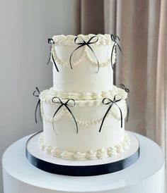 three tiered white cake with black bows on top