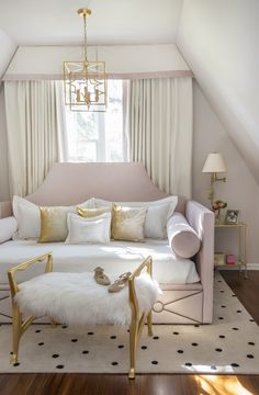 a white couch sitting under a window in a living room next to a chair and ottoman