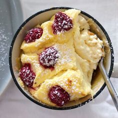 a bowl filled with ice cream covered in raspberries and topped with powdered sugar