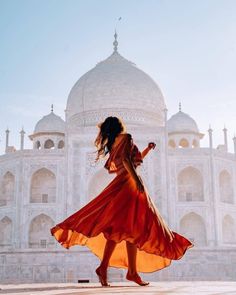 a woman in an orange dress is walking near the tajwa