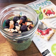 a jar filled with blueberries and almonds next to a magazine on a table