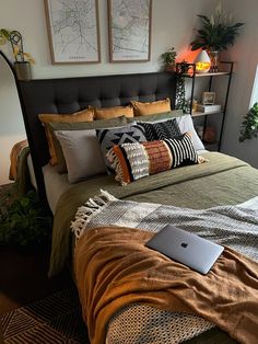 a laptop computer sitting on top of a bed next to pillows and blankets in a bedroom