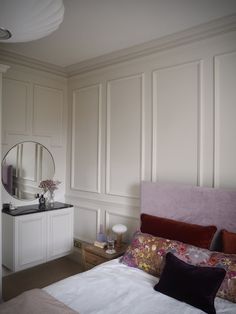 a bedroom with a bed, dresser and mirror in the corner next to each other