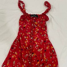 a red dress with flowers on it laying on a white sheeted bed coverlet