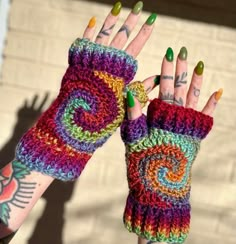 a woman's hand with multicolored crocheted fingerless gloves on it