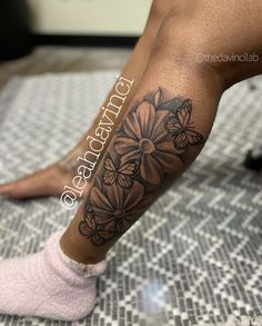 a woman's leg with flowers on it and a butterfly in the middle of her leg