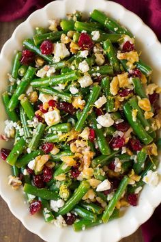 a white bowl filled with green beans and cranberries on top of a wooden table