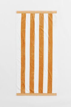 an orange and white striped towel hanging on a wall in front of a white background