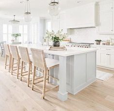 a large kitchen with white cabinets and an island in the middle, surrounded by chairs