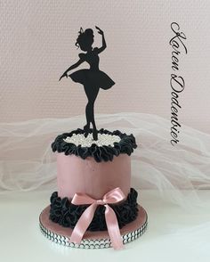 a pink and black cake with a silhouette of a ballerina on top, sitting on a table