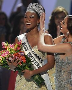 two beautiful women standing next to each other in front of a crowd at a competition