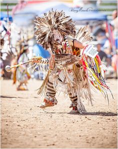 a person in costume holding a baseball bat on a dirt field with people watching from the sidelines