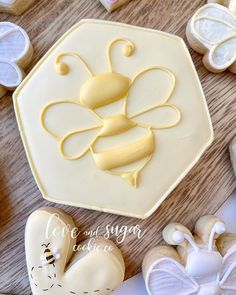 some cookies are sitting on a table and decorated with icing, honeybees, and hearts