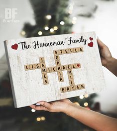 a person holding up a wooden sign that says the american family with hearts on it