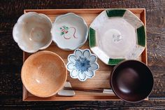 bowls and spoons are arranged on a wooden tray