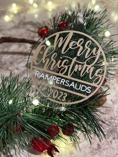 a glass ornament with the words merry christmas on it and pine branches around it